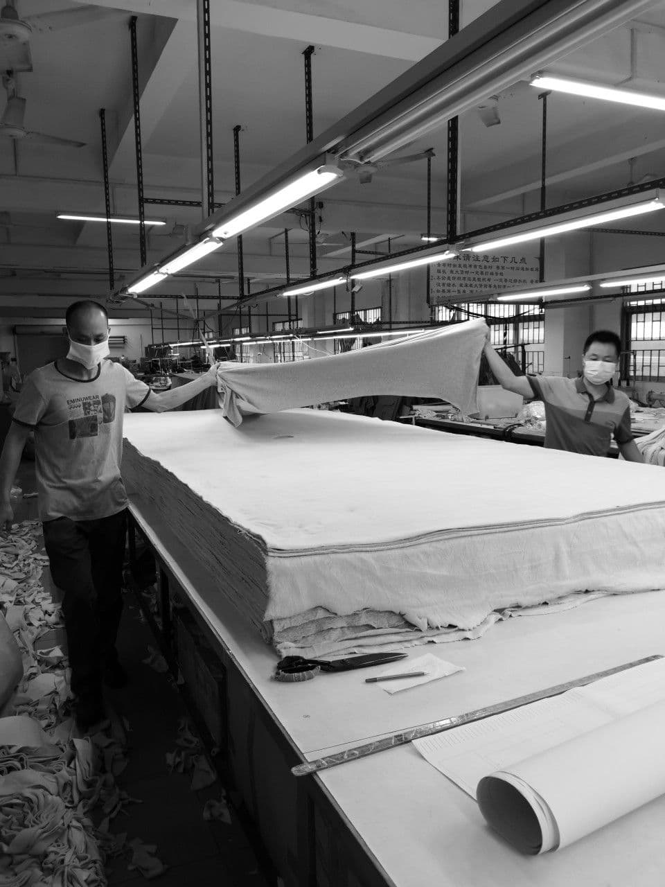 Workers spreading fabric across a cutting table